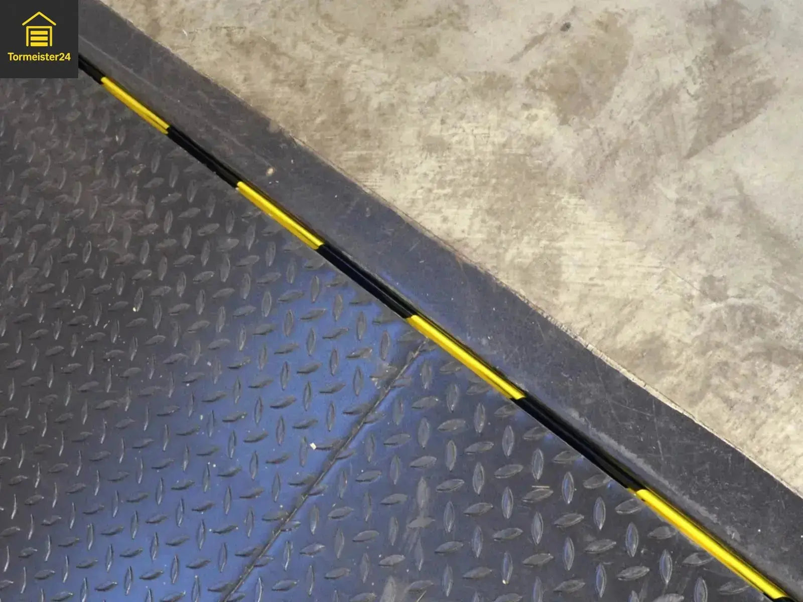 DockMag Hinge SAMLH 60 magnetische Spaltabdichtung für die hintere Scharnierseite von Verladebrücken und Rampen mit 60-mm-Dichtlippe, 100-mm-Magnetfuß und schwarz-gelbem Gewebe gegen Zugluft, Staub und Schädlinge.