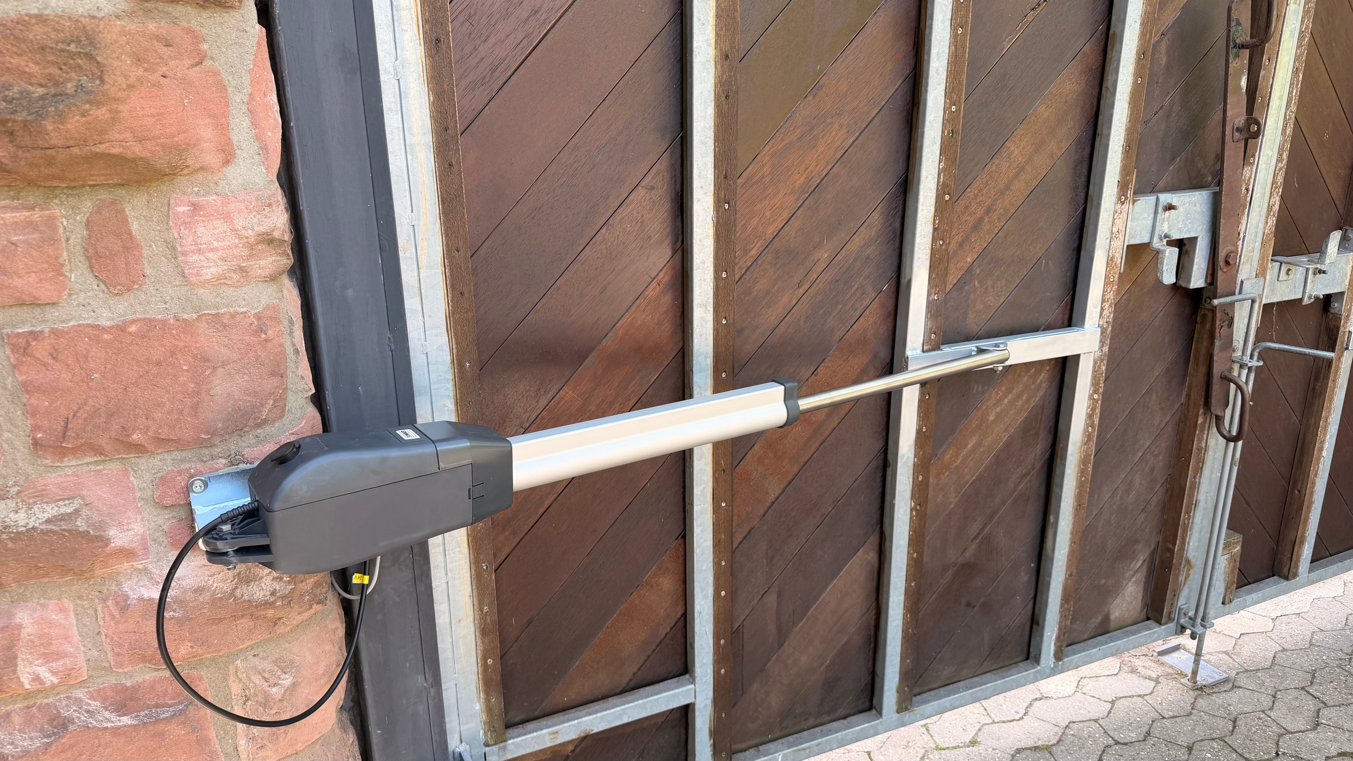 Einflügeliges automatisches Drehtor an einer Einfahrt mit passendem Drehtorantrieb für lange Torflügel, große Pfosten und komfortable Toröffnung.